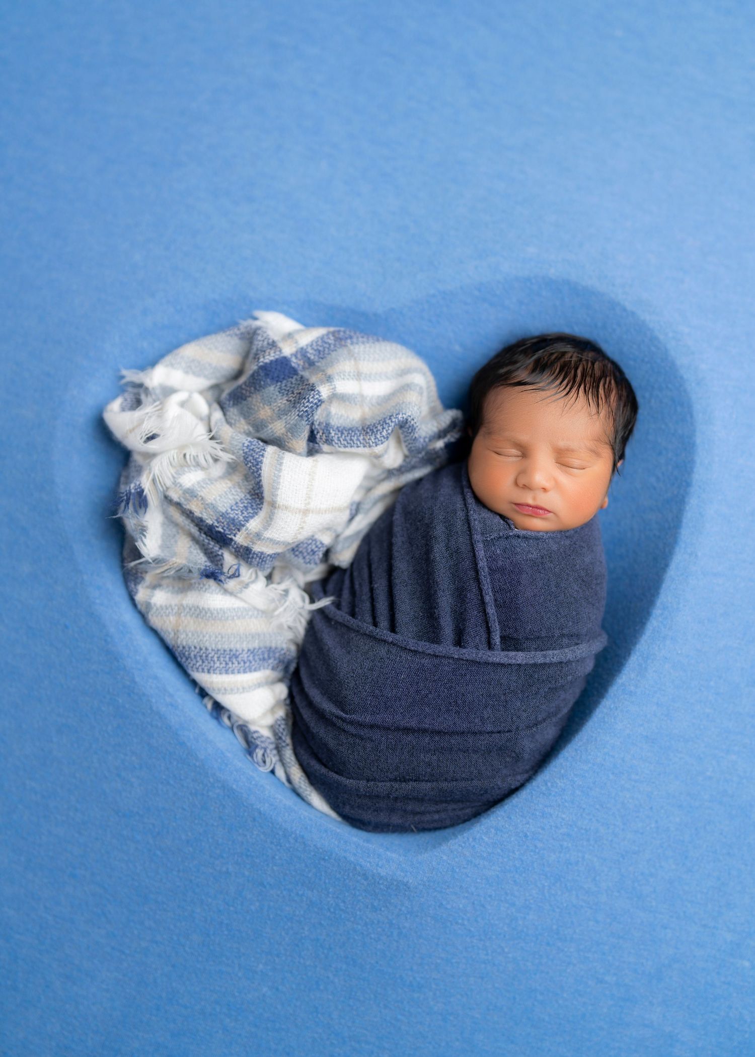 newborn baby boy wrapped in blue in heart shape