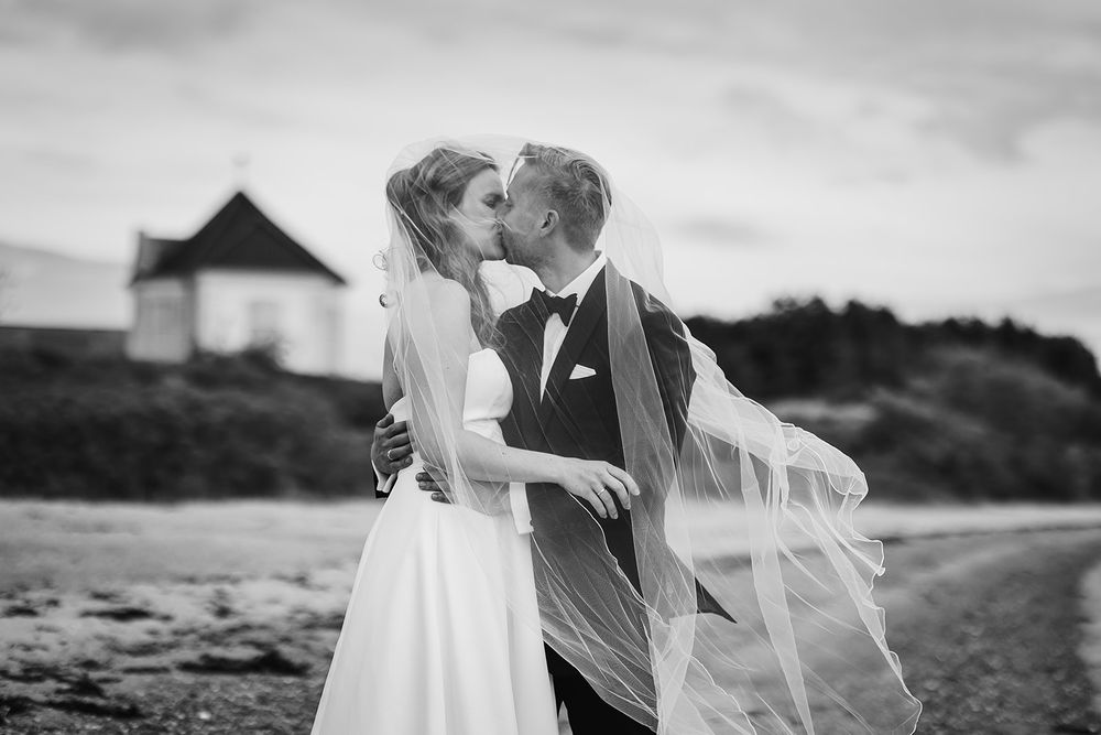 Black and white wedding photography collage showing romantic moments with a flowing veil on a beach at sunset.