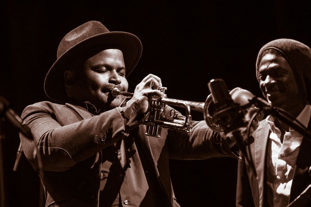 Two jazz musicians playing trumpet together in dramatic black and white lighting.