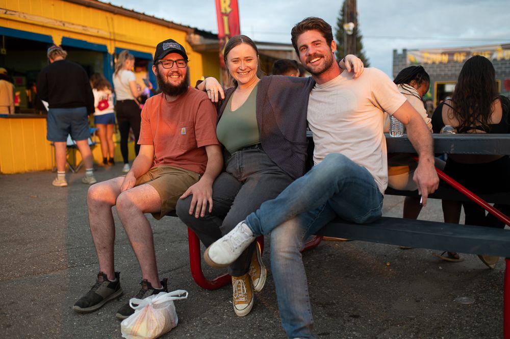 Friends enjoying a casual evening at an outdoor festival with food vendors and picnic tables.