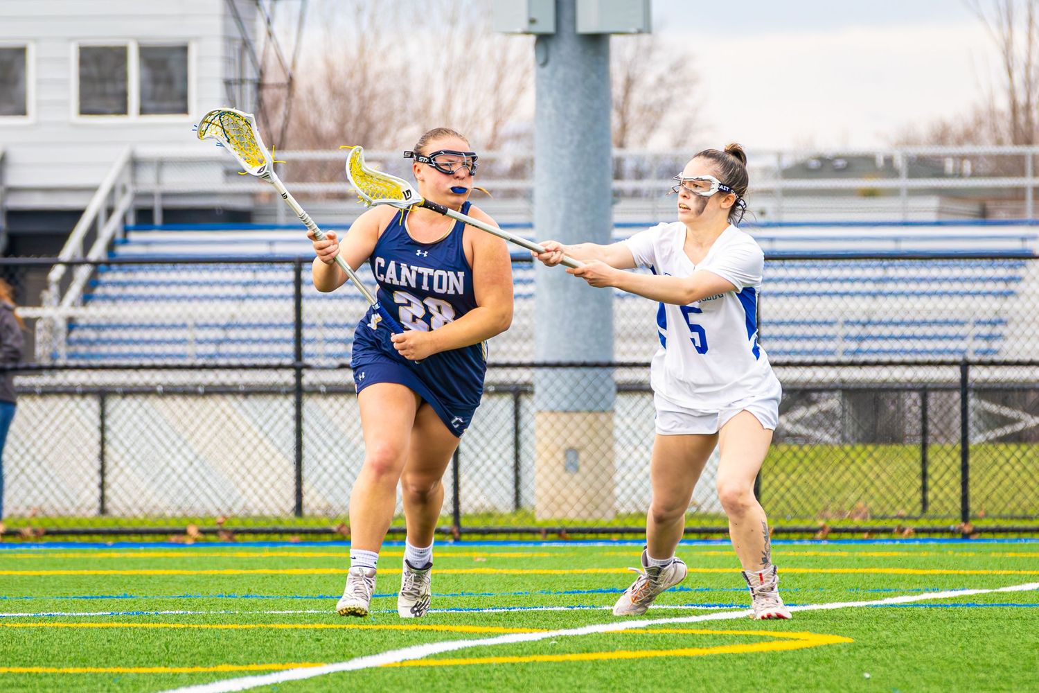 Lacrosse players demonstrate skillful maneuvers during a competitive match on the field.