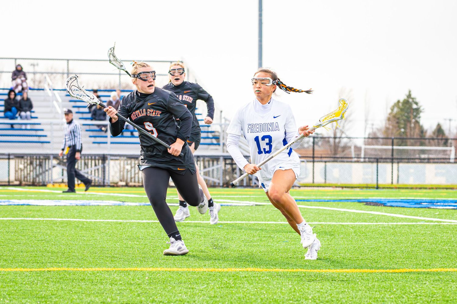 Athletes battle for possession during an intense lacrosse match on the turf field.