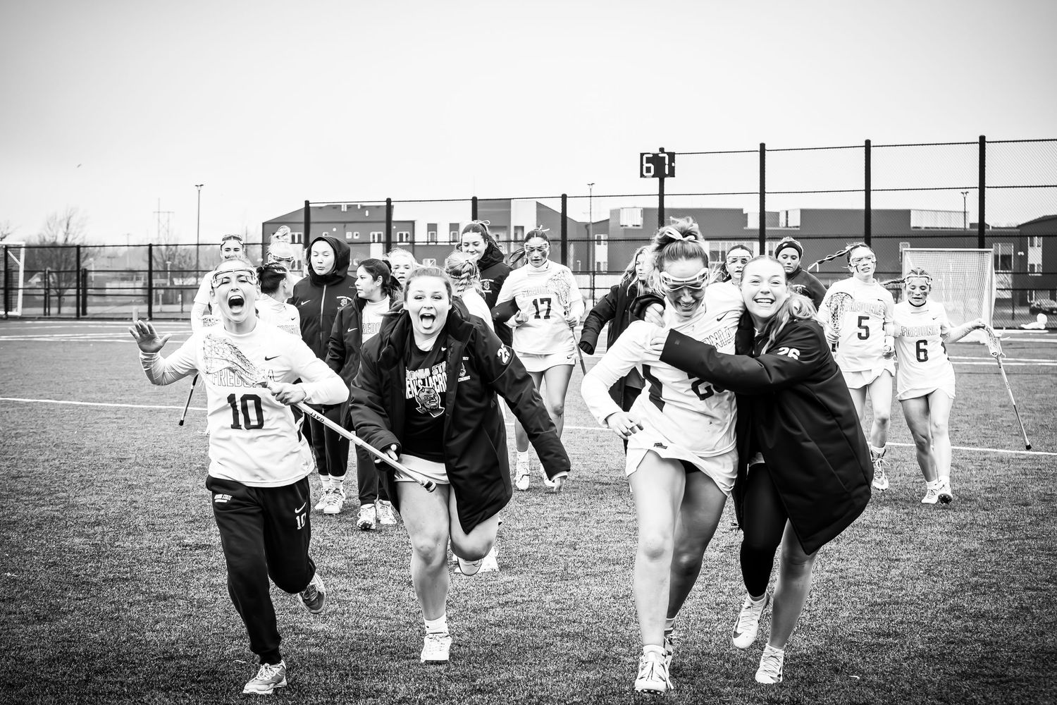 Athletes run across the field in black and white action shot of a sports match.
