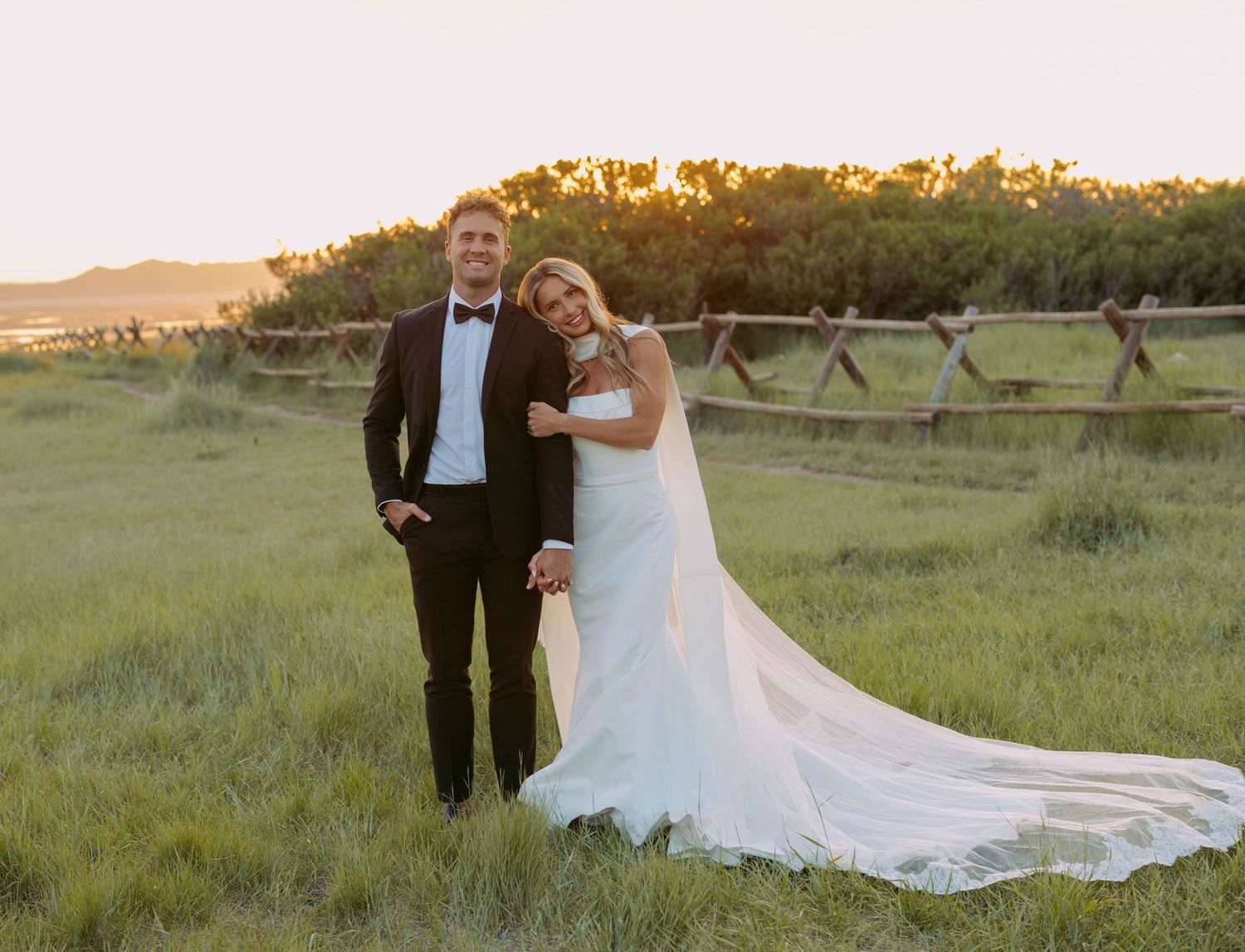 Couple shares tender moment in mountain meadow during golden hour.