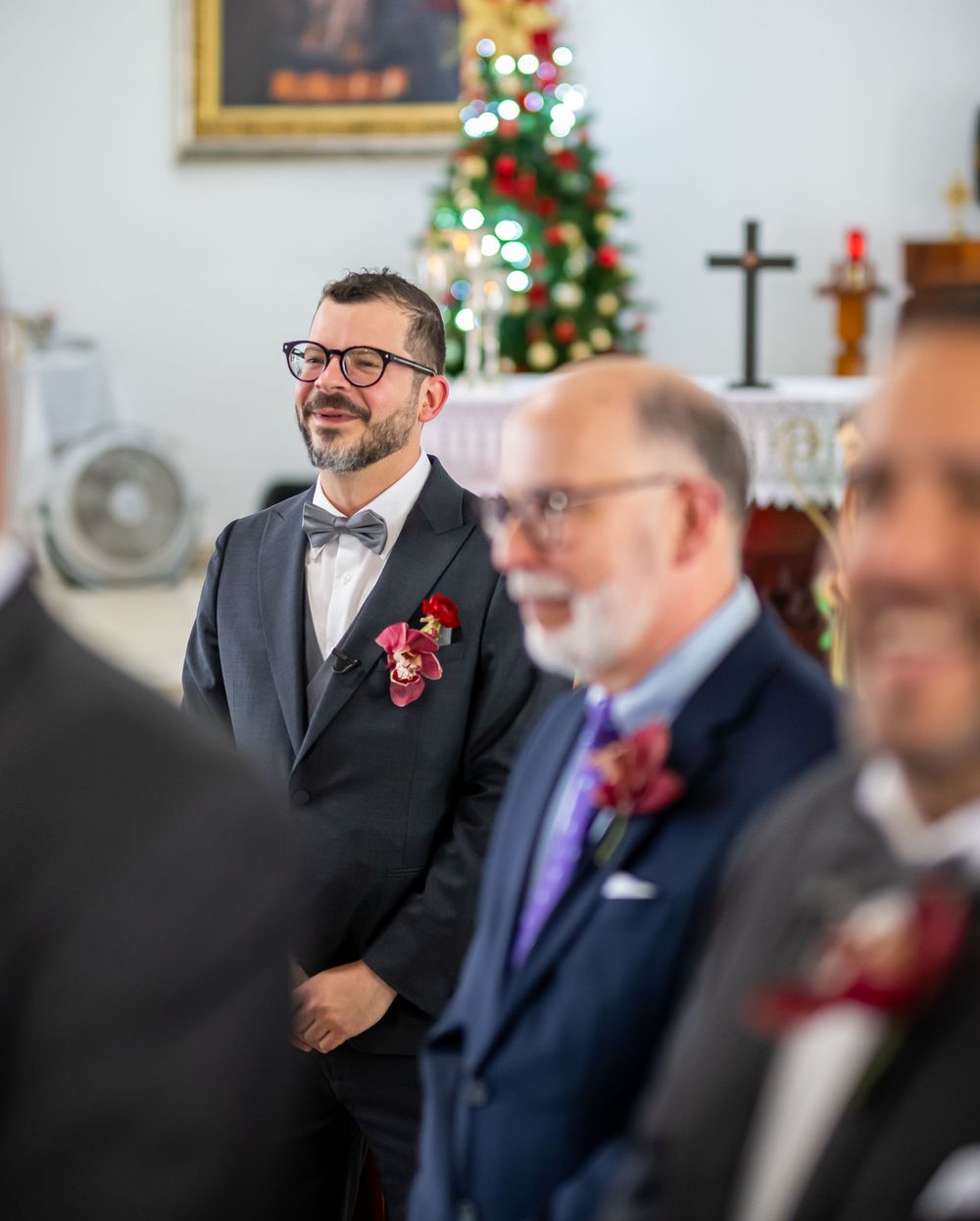 Wedding ceremony in church with Christmas tree and festive decorations visible.
