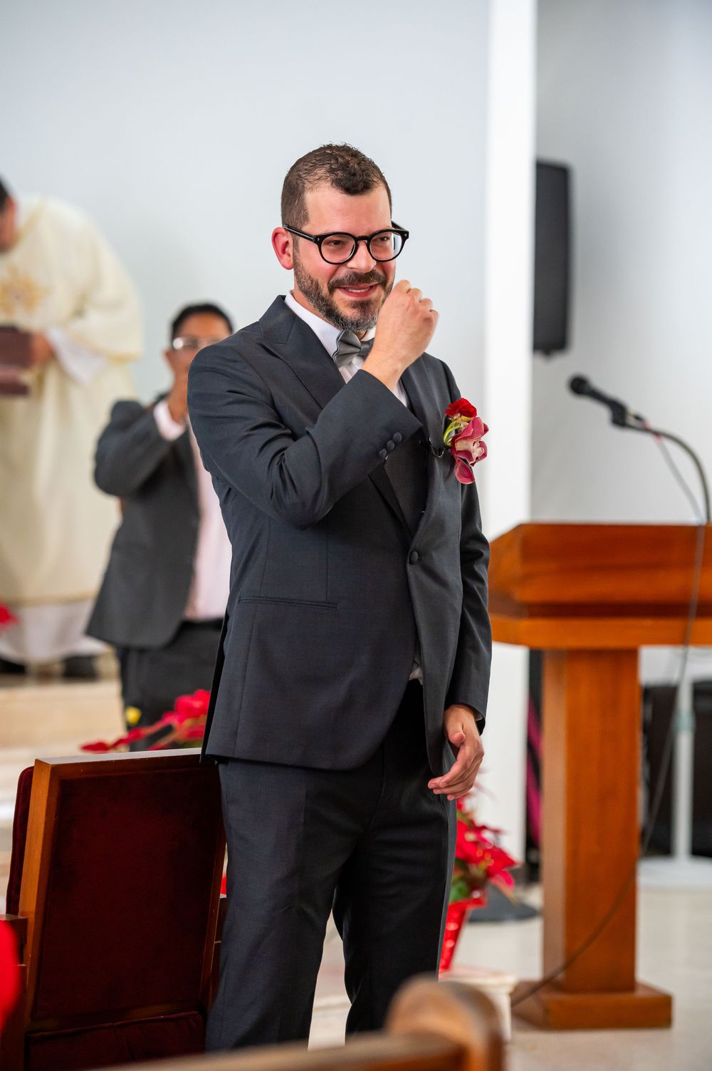 Groom smiling emotionally during wedding ceremony in church setting.