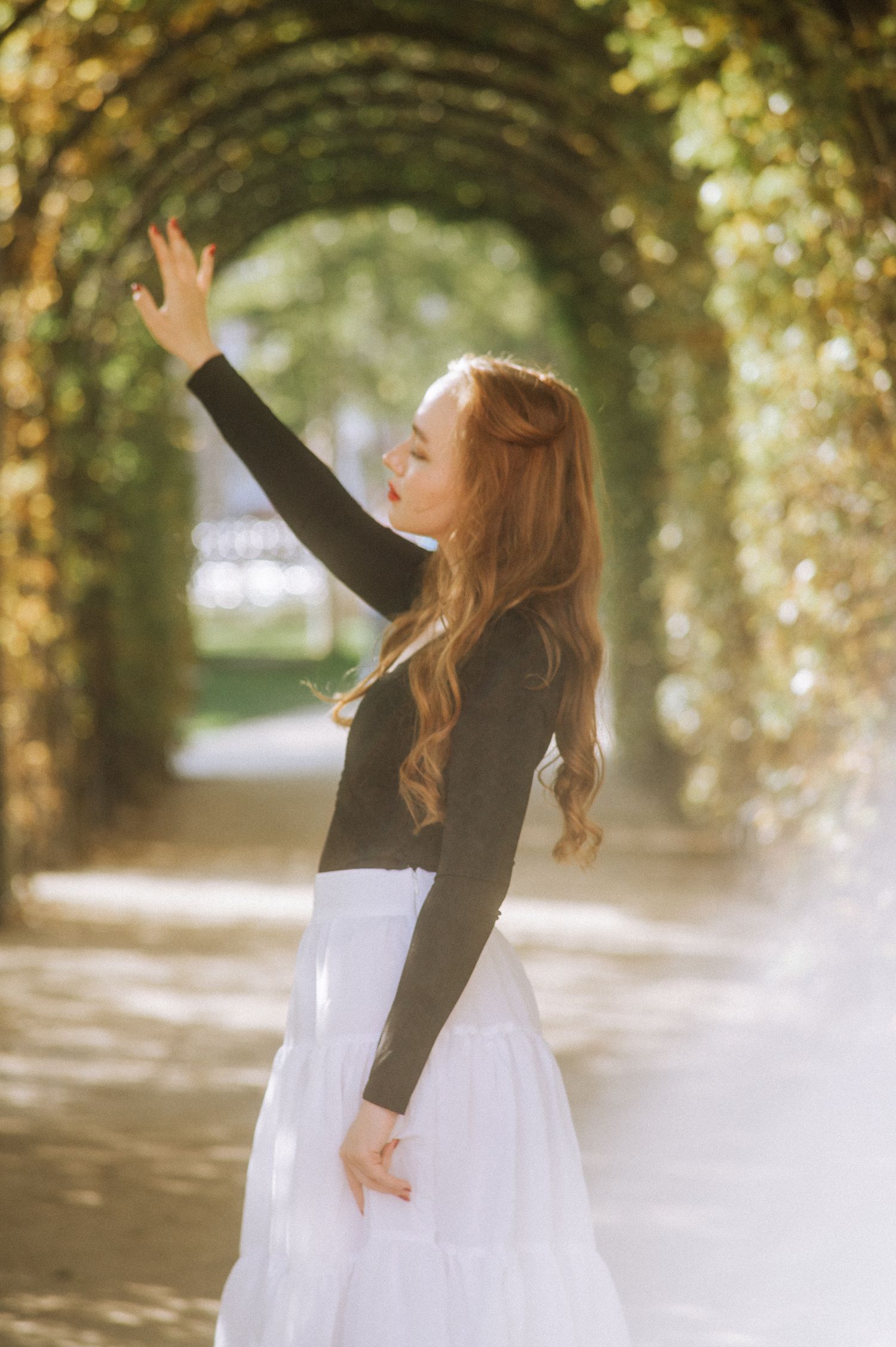 A candid shot of Diana walking through Vondelpark surrounded by green arch and sunlight.