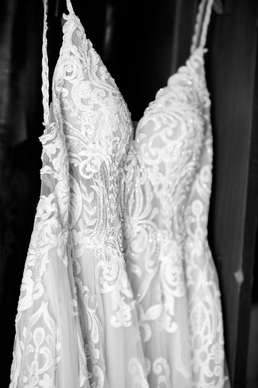 Black and white detail shot of a wedding dress showing elaborate lace patterns.