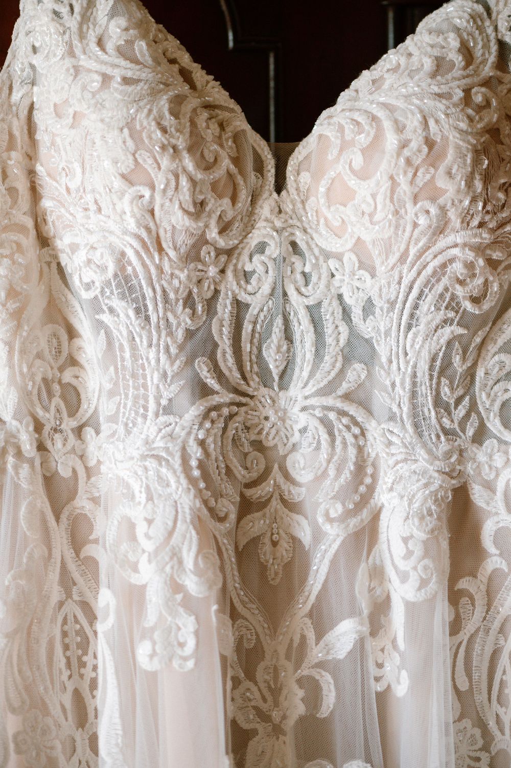 Detailed close-up of wedding dress bodice showing intricate lace and beading patterns.