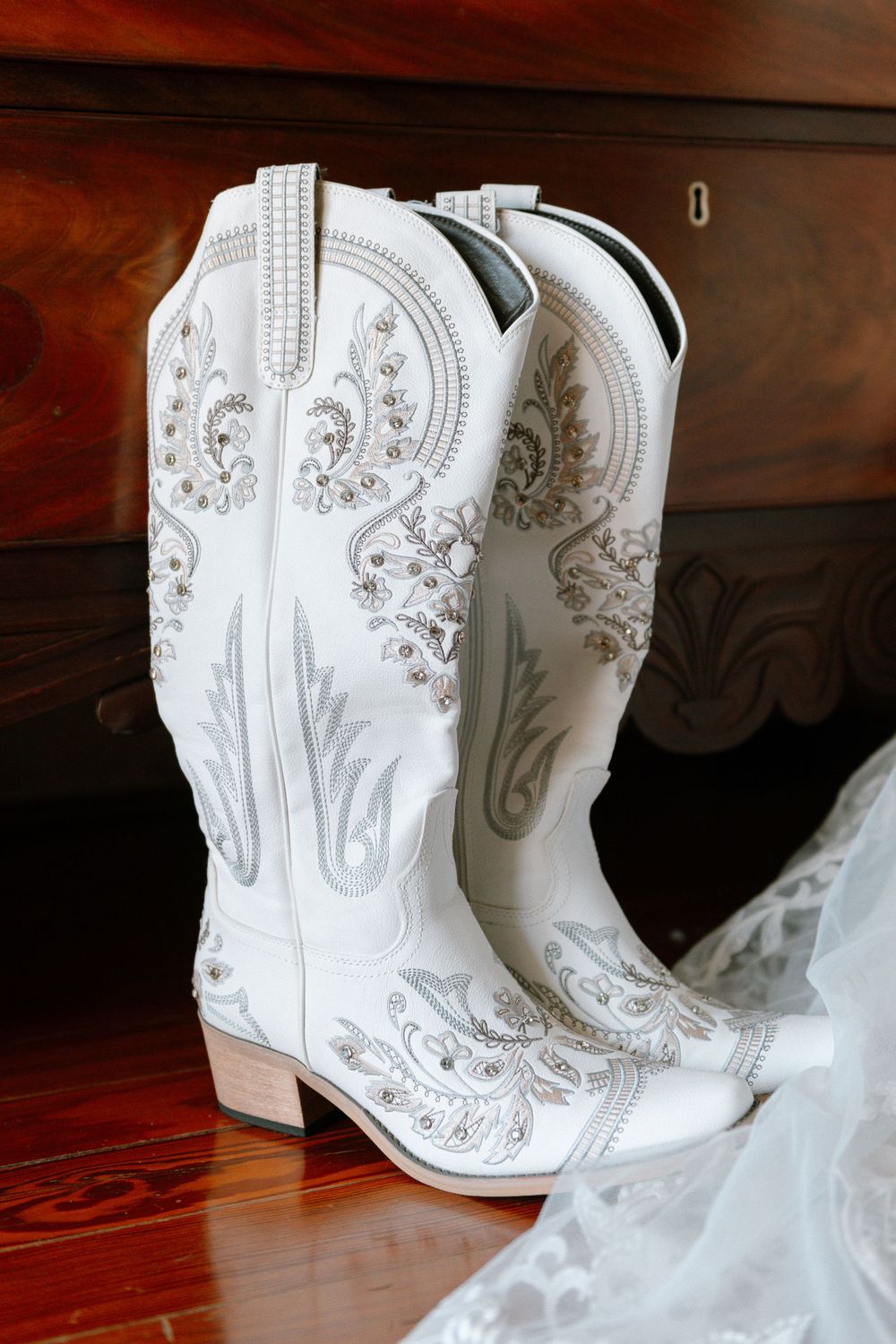 White leather cowboy boots with ornate silver embroidery and decorative stitching details.