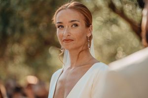 A close-up bridal portrait in warm sunlight showcasing elegant makeup and jewelry in Crete.