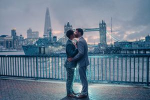 A romantic moment between a couple by Tower Bridge in London at dusk with the Shard in the background.