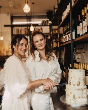 Wedding celebration in rustic bar setting with wedding cake and vintage lighting fixtures.