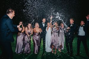 Wedding party celebrates at night with champagne spraying and sparklers at Ham Polo Club
