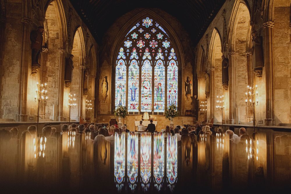 A stunning church interior with gothic stained glass windows and reflective flooring creates a mirror effect.
