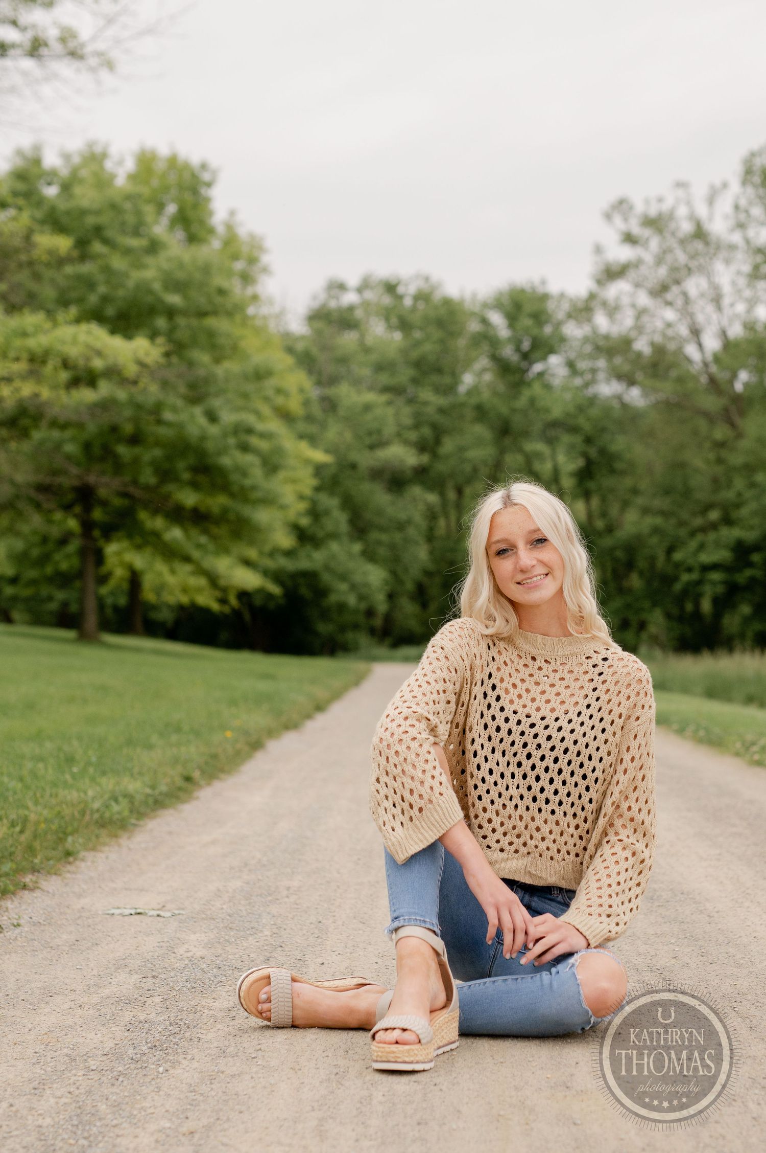 Summer portrait on a country path showcasing a knit tan sweater and sandals.