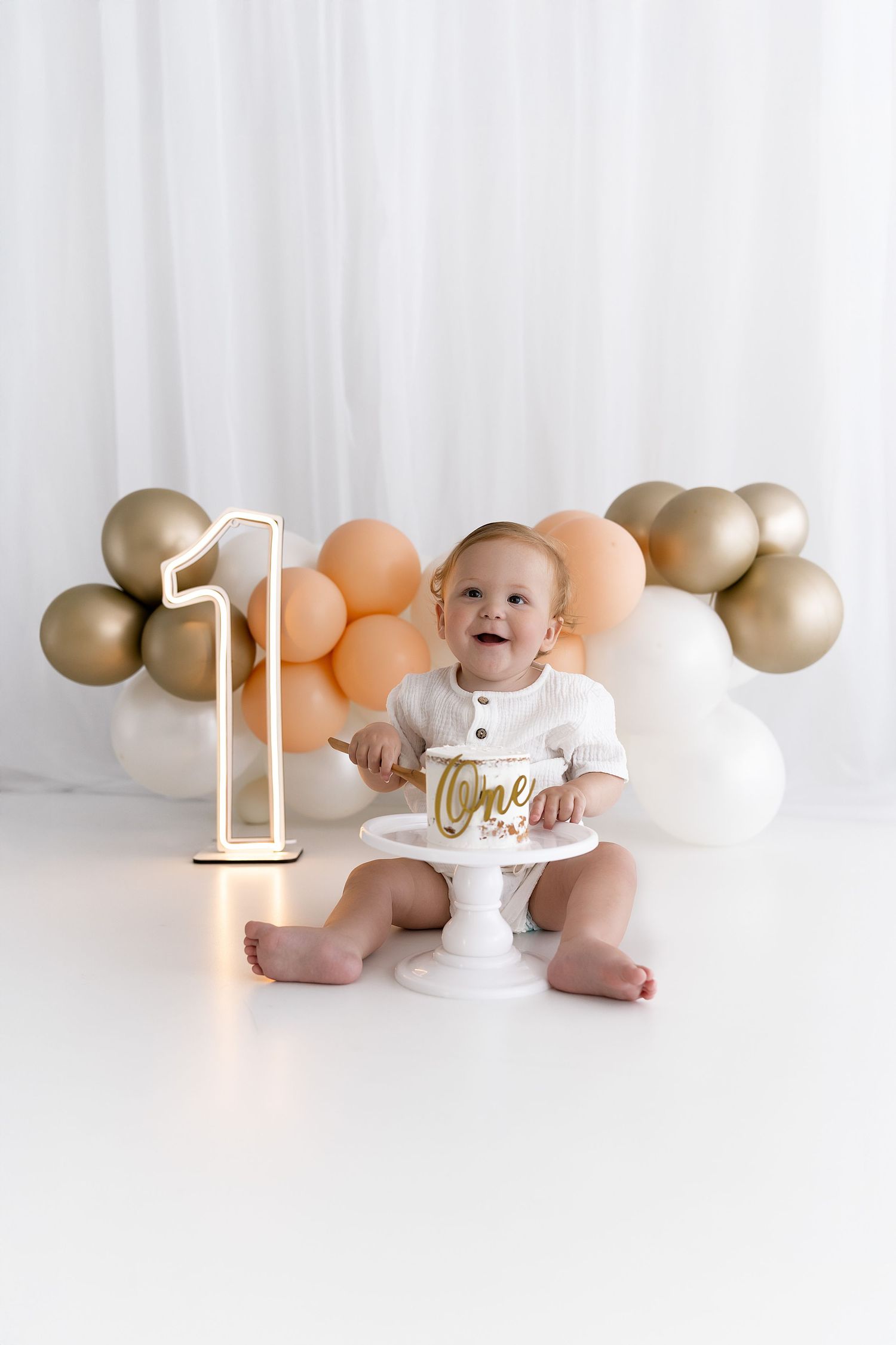 Baby's first birthday setup with cake, balloons, and number one display.