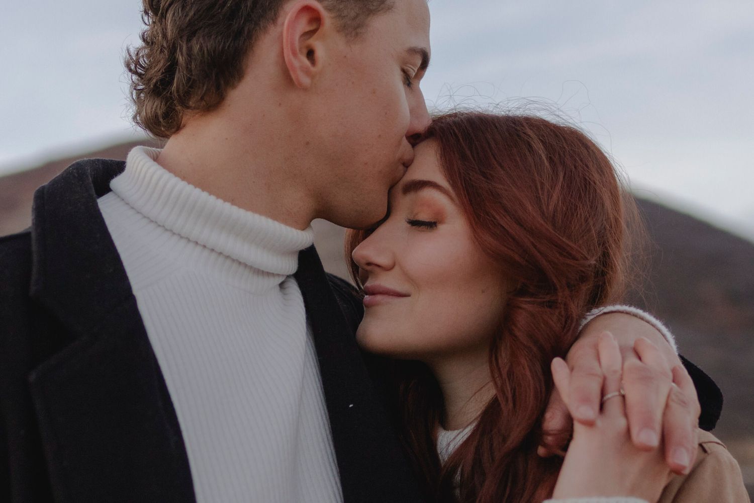 He kisses her forehead. Close up.