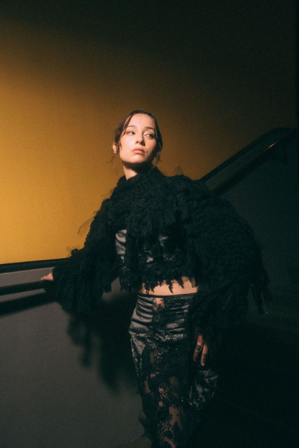 Dramatic fashion photo featuring black lace outfit against warm golden background.