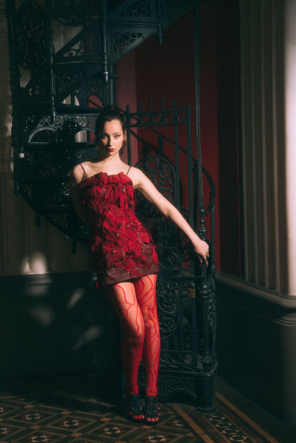 Fashion shot with red dress against stained glass windows in historic building.