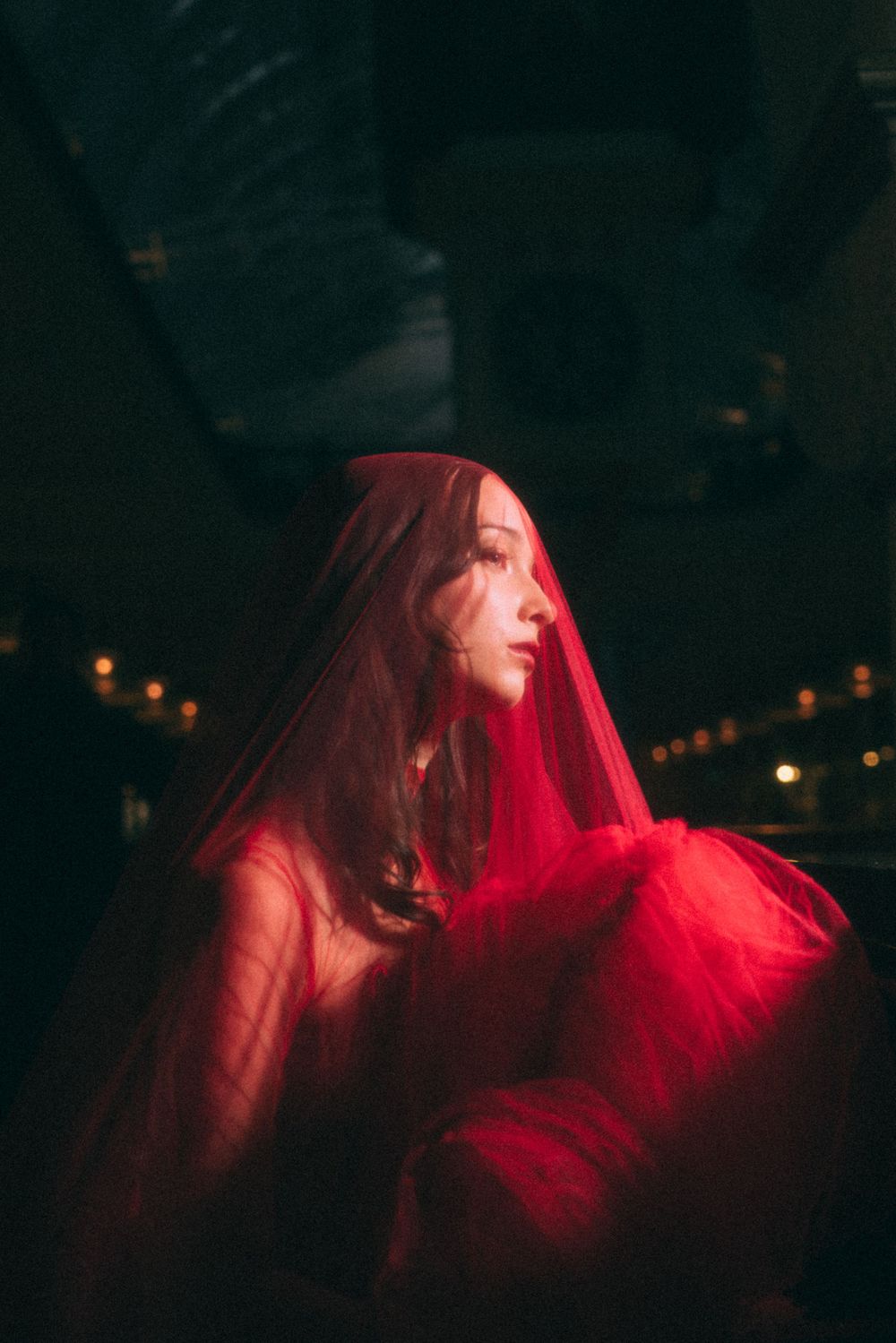 Moody photograph with red lighting and flowing fabric creating a dreamlike atmosphere.