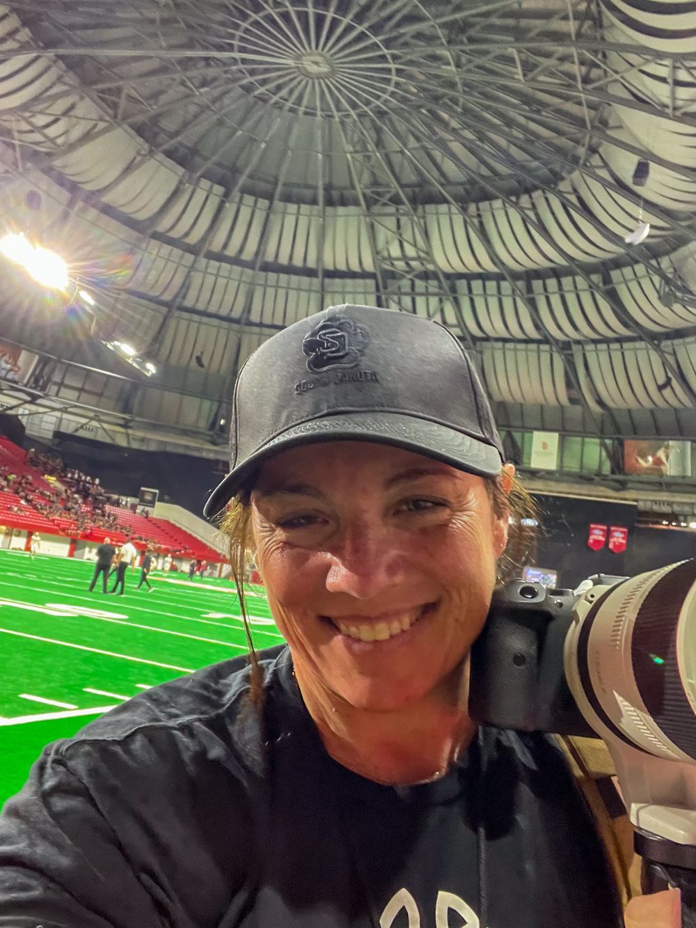 Portrait of Sally Lombard with her camera at the Dakota Dome before a football game