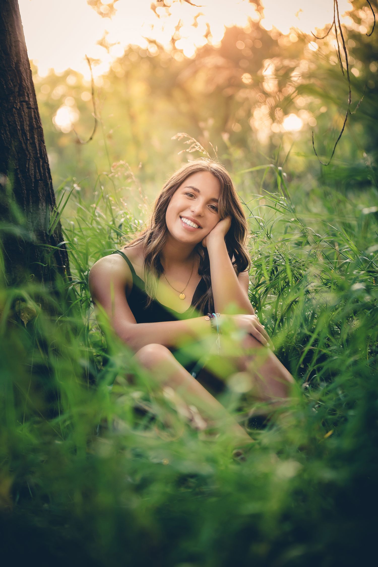 Portrait of someone sitting in lush green grass during golden hour.