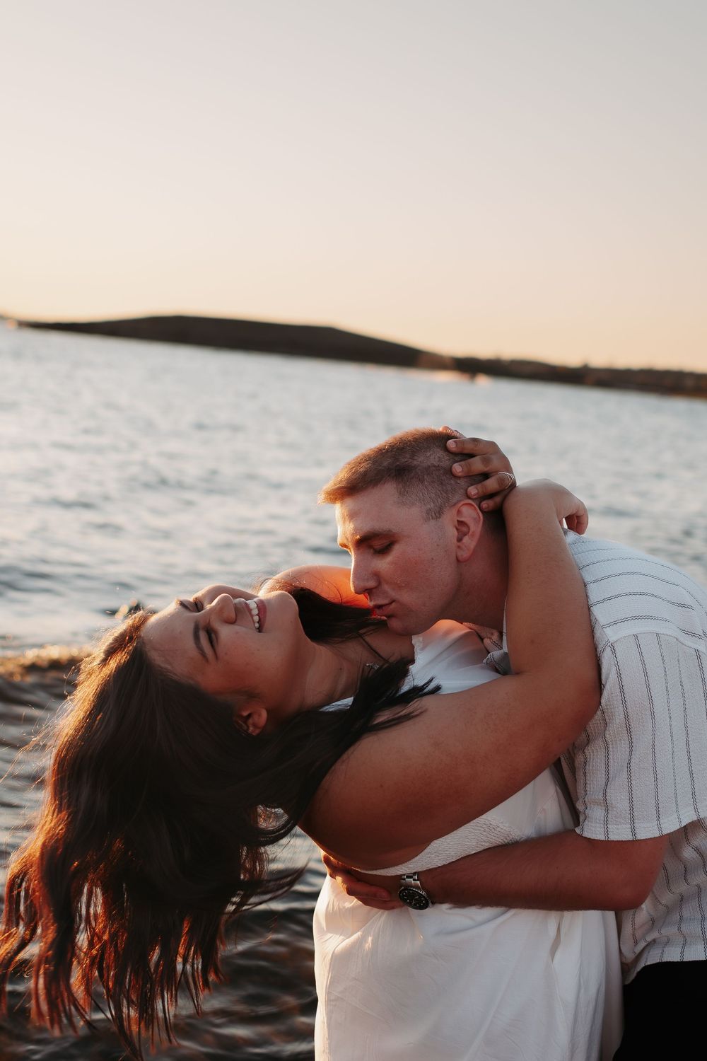 Romantic sunset beach photoshoot with couple embracing by the ocean.