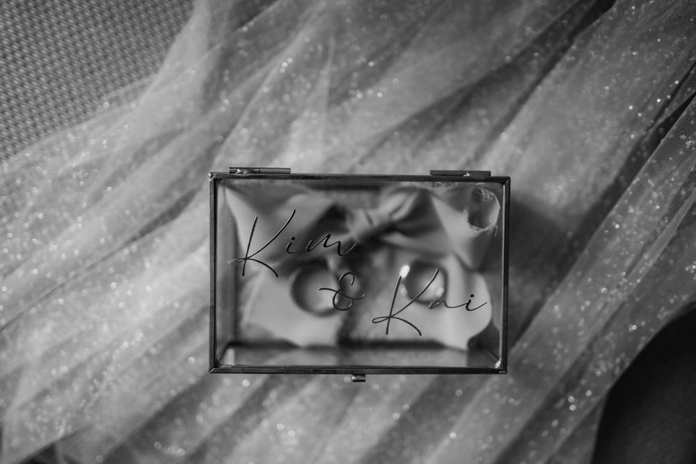 Wedding rings displayed in a black and white photograph against a textured background.
