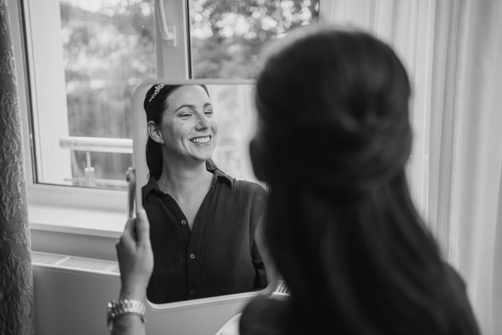 Black and white reflection of bridal preparation moment.