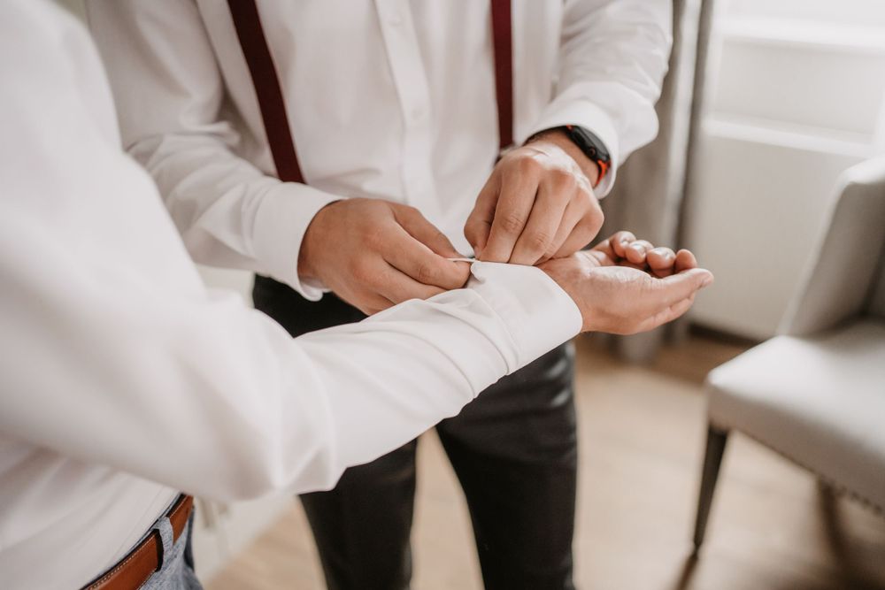 Close-up of hands adjusting formal attire cuffs and buttons.