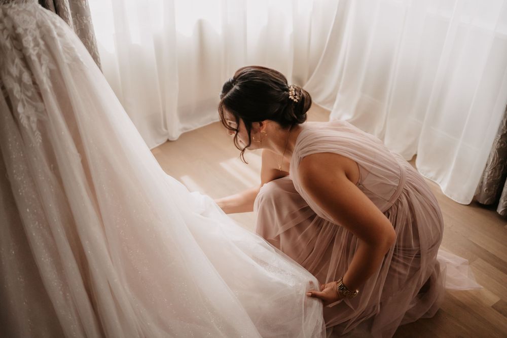 Preparation moment with wedding dress in soft natural light.