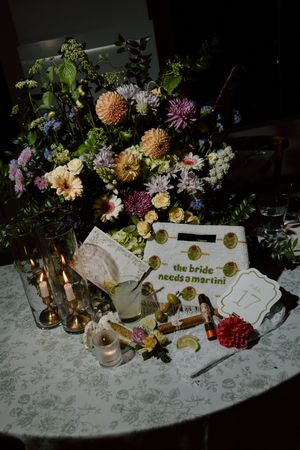 Colorful wedding table with floral centerpiece, candles, martini glass, and a sign reading the bride needs a martini.