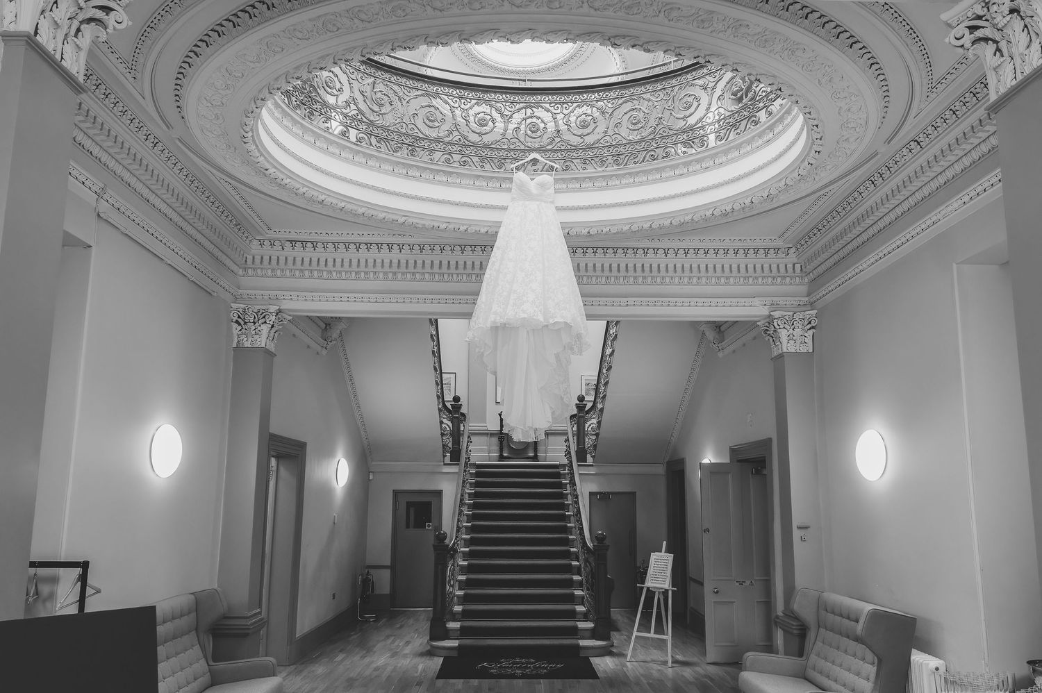 Elegant white hallway with ornate crown molding, domed skylights, and a grand staircase in a historic building interior. Wedding dress