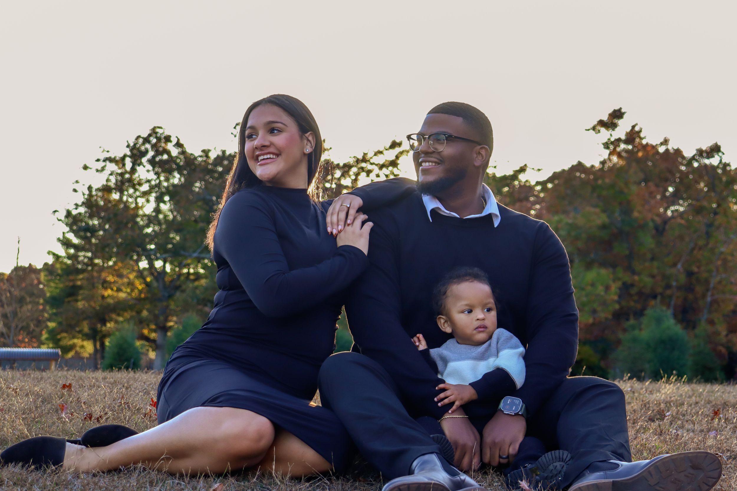 A family sits together outdoors in coordinating navy blue outfits.