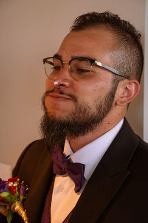 A series of close-up shots showing someone in a black suit and purple bowtie smiling from different angles.
