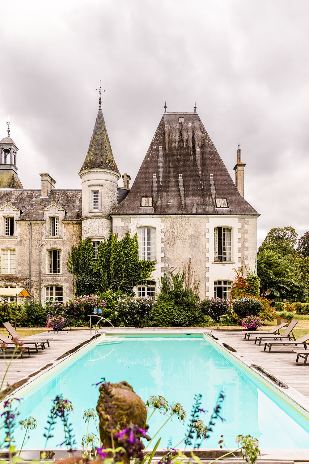 Luxury chateau with swimming pool and lounge chairs showcasing classic French architecture.