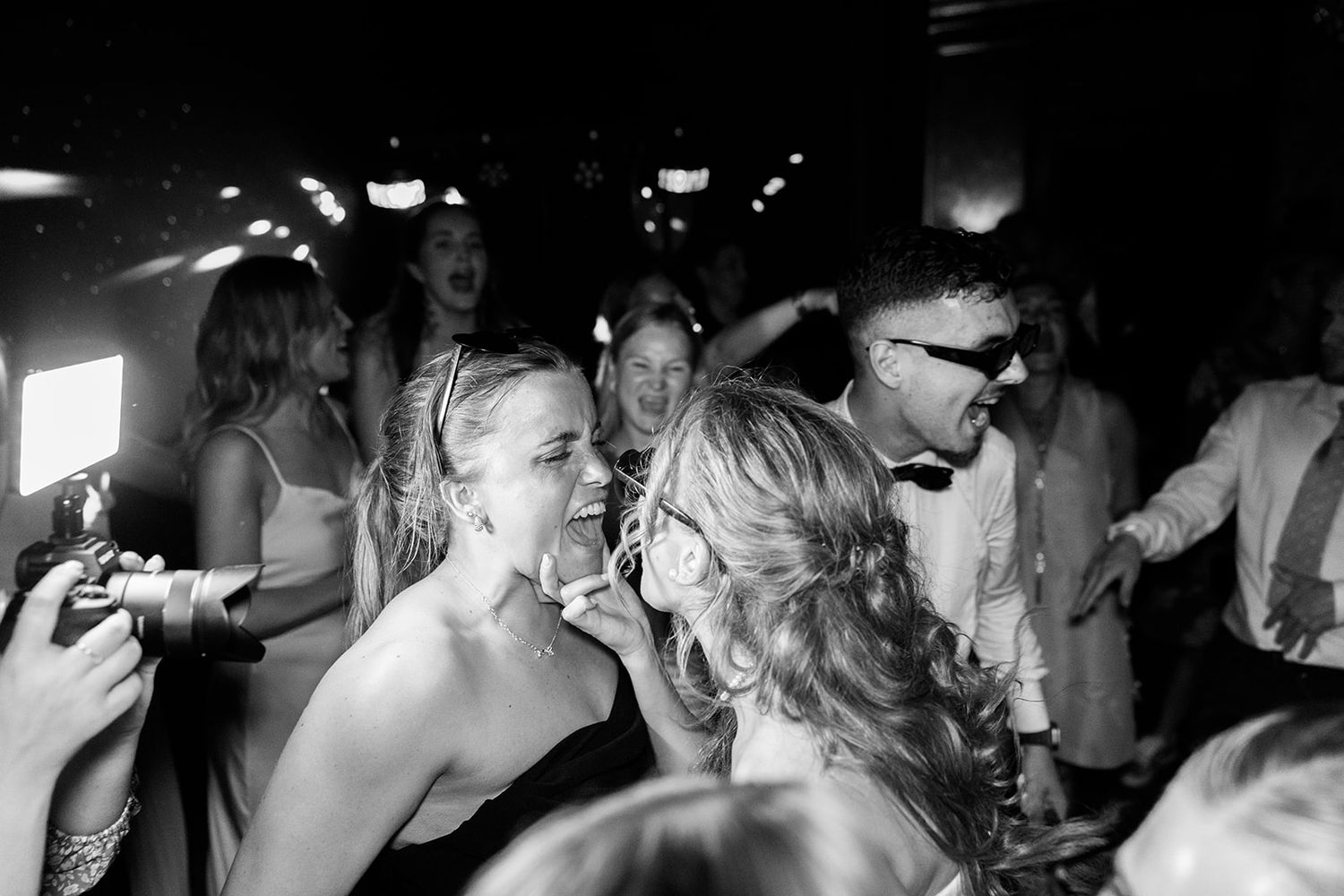A group of people dancing and celebrating at a dimly lit nightclub or party venue.