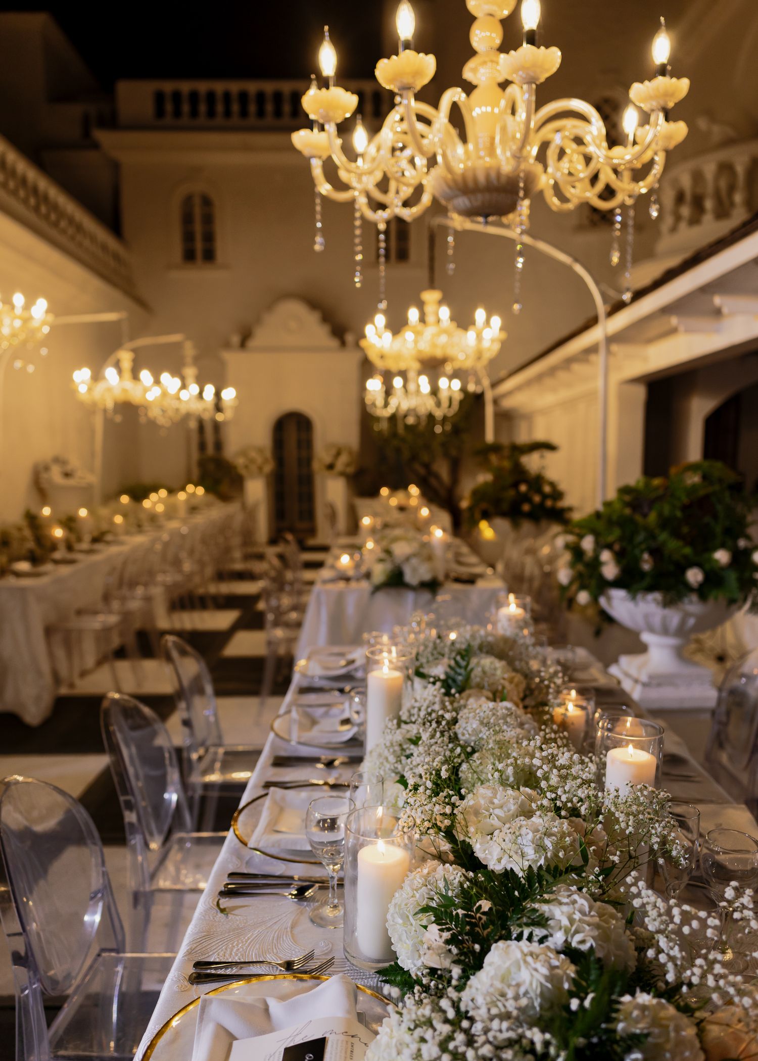 Elegant wedding venue with blue chairs, chandeliers, and floral arrangements on tables.