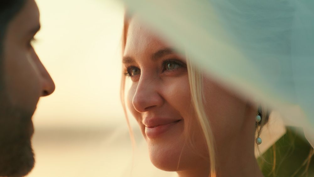 A close-up profile view of someone smiling while engaged in conversation against a soft blurred background.
