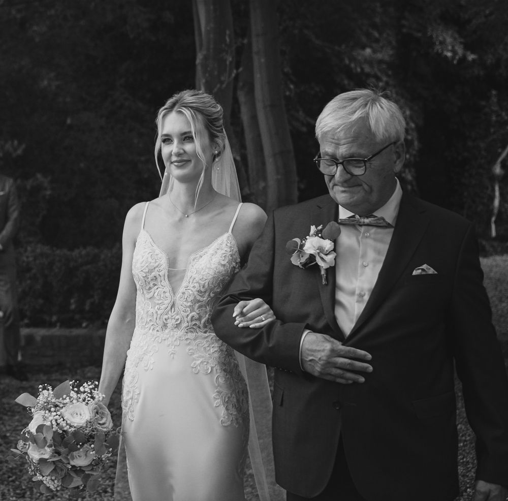 A heartwarming moment at a wedding ceremony as a couple walks arm in arm down a garden path.