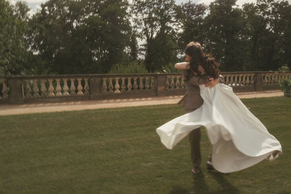 A couple dances on a lawn terrace with stone balustrade as the bride's white dress flows gracefully in the wind.