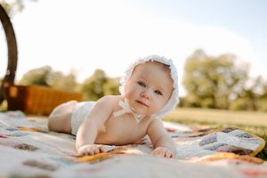 Sunlit outdoor portrait with patchwork quilt and wicker basket details.