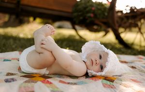 Baby lying on colorful patchwork quilt during golden hour photoshoot.