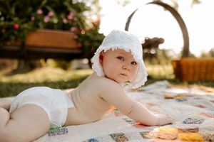 White bonnet and patchwork quilt details photographed in natural sunlight outdoors.