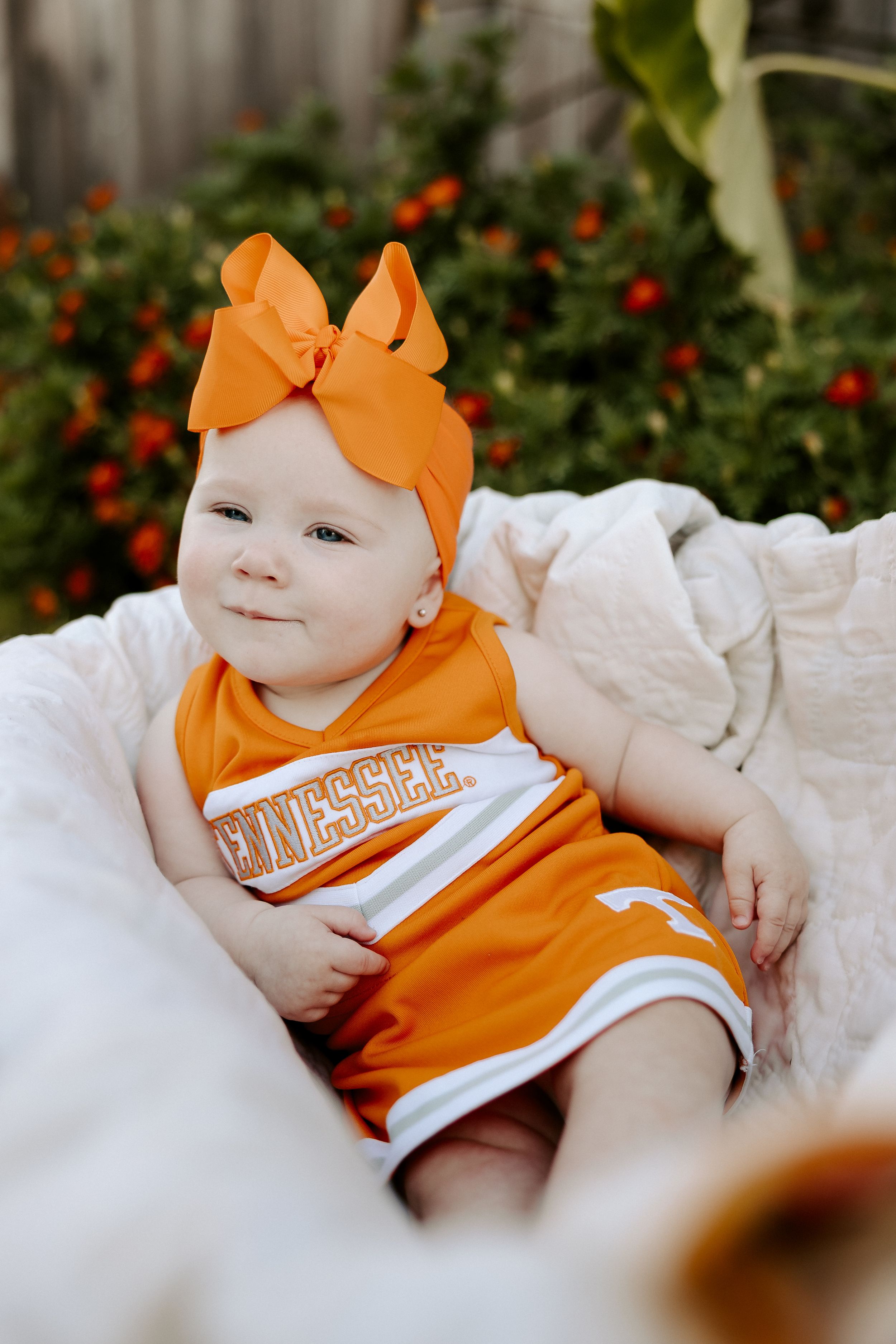 Orange and white outfit photographed against floral garden background.