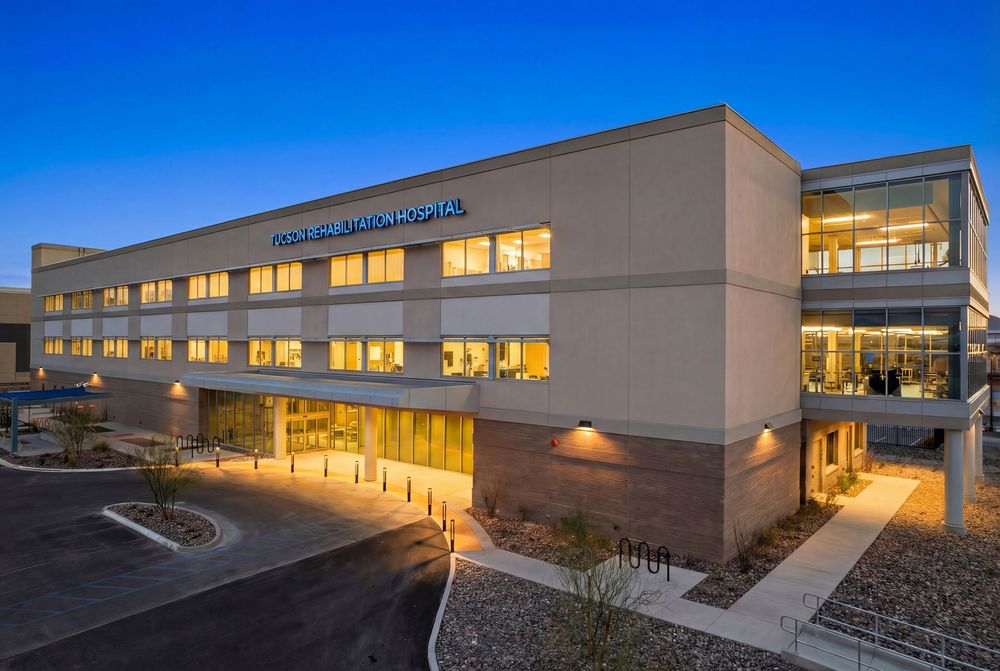 Modern commercial building exterior with illuminated windows at dusk showcases sleek architectural design and landscaping.