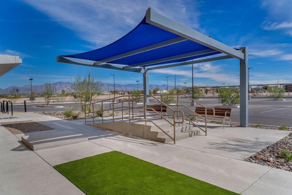 Modern industrial building exterior with covered walkways and landscaping under bright blue desert skies.
