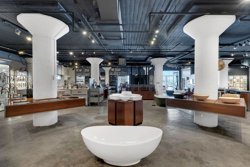 Modern office interior with white pillars, wood furniture, and open floor plan design showcases industrial ceiling elements.