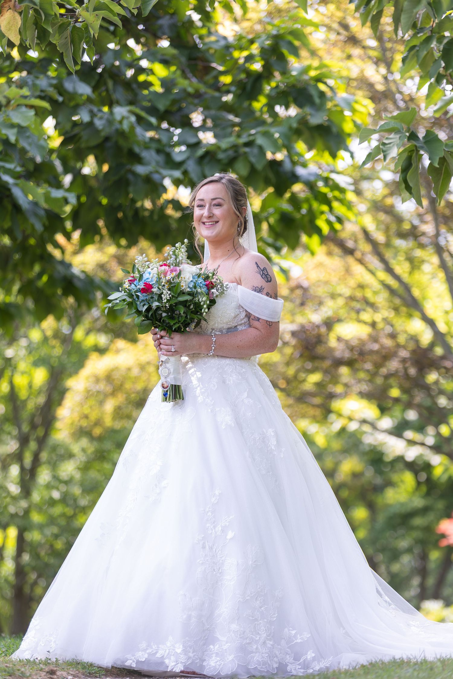 A wedding party stands in a lush garden setting with vibrant greenery and natural lighting.